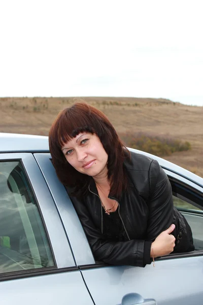 Young brunette looks out the car window — Stock Photo, Image