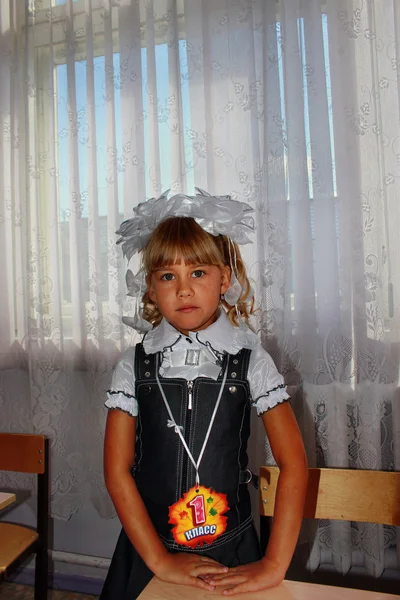 Gadis dengan kaset kelas pertama berdiri di dekat meja — Stok Foto