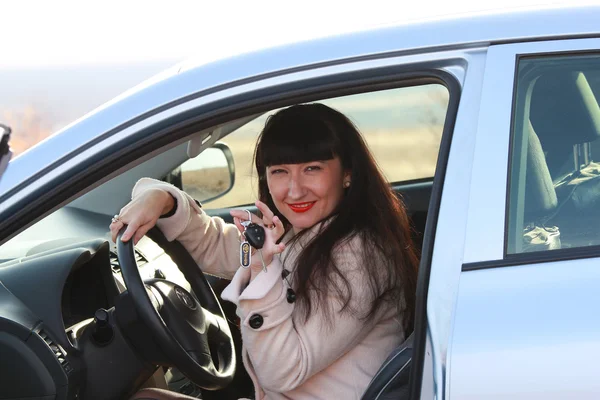 Mulher feliz dirigindo um carro mostra a chave — Fotografia de Stock