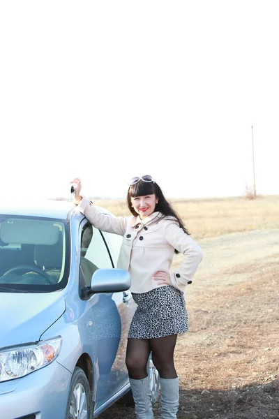 Linda morena na frente de seu carro com as chaves na mão — Fotografia de Stock
