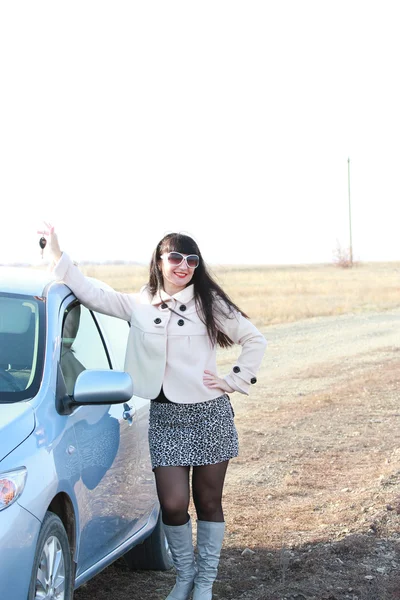 Menina de óculos de sol com uma chave na mão perto de um carro — Fotografia de Stock