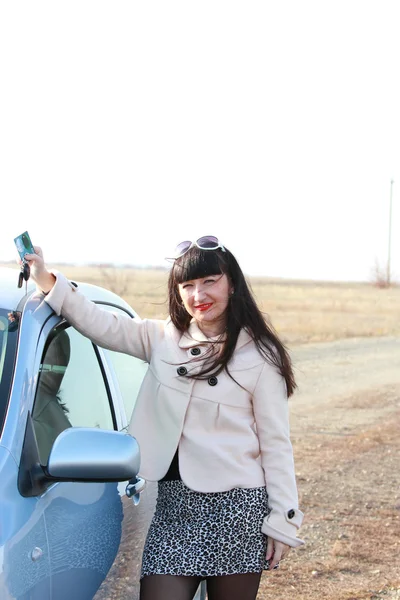 Menina perto de um carro com um cartão de crédito e chaves na mão — Fotografia de Stock