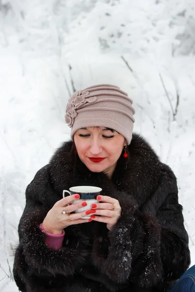 Chica en el bosque de invierno bebiendo té de una taza — Foto de Stock