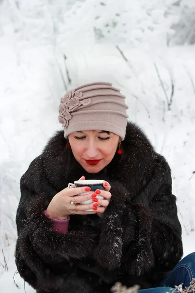 Hermosa chica sosteniendo una taza de té en el bosque de invierno — Foto de Stock