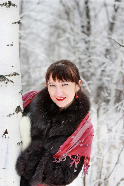 Beautiful woman looks out from behind a birch — Stock Photo, Image