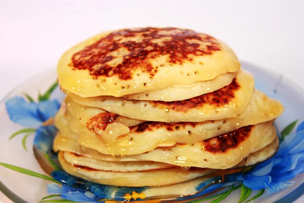 Maslenitsa.blinchiki mit Honig auf einem Teller — Stockfoto