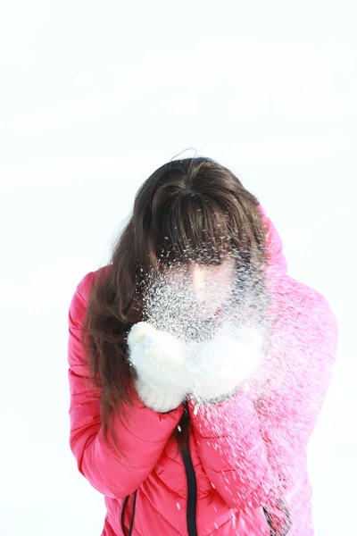 Jovem menina em luvas brancas sopra longe a neve das mãos — Fotografia de Stock