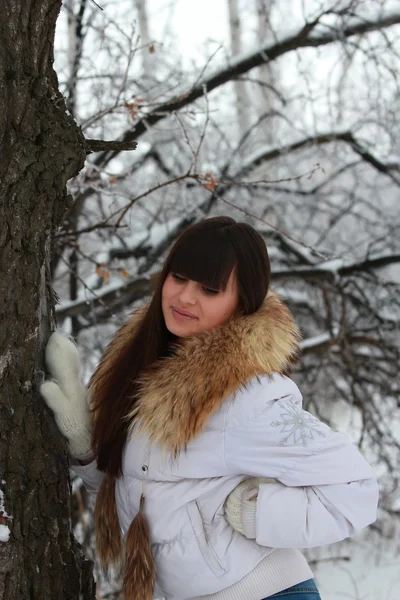 A young girl in a white jacket near a tree — Stock Photo, Image