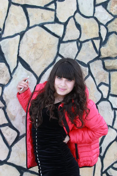En flicka i en svart klänning nära en stenmur — Stockfoto