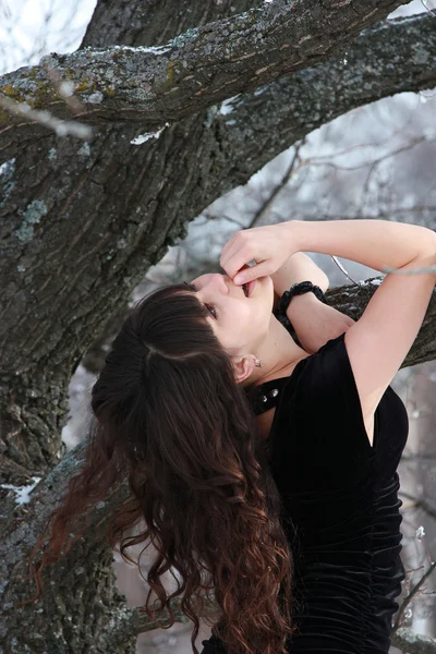 Menina de cabelos compridos fica perto de uma árvore, levantando a cabeça para cima — Fotografia de Stock