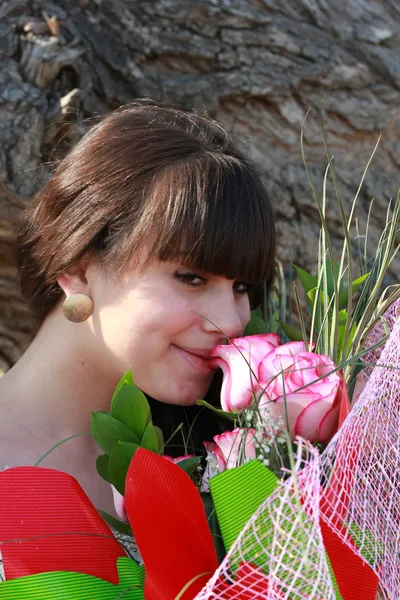 Brunette enjoys the scent of roses — Stock Photo, Image