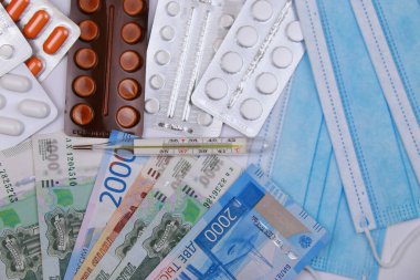 Coronavirus, bir salgın. Koruyucu tıbbi maske, haplar, termometre ve Rus parası.