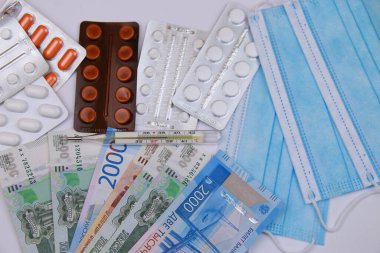 Coronavirus ve grip salgını. Yüksek ateş. Tıbbi maske, termometre, haplar, Rus parası..