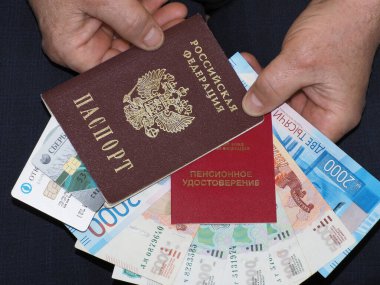 Emeklilik belgesi, banka kartları ve para bir adamın elinde.