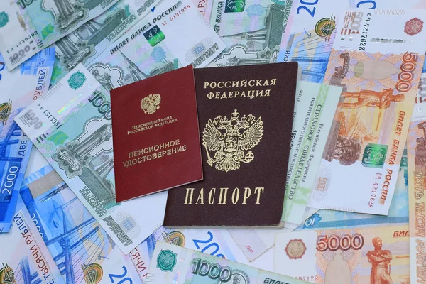 Belgeler: Emeklilik sertifikası, zorunlu emeklilik sigortası belgesi ve Rus parasının arka planında Rus pasaportu