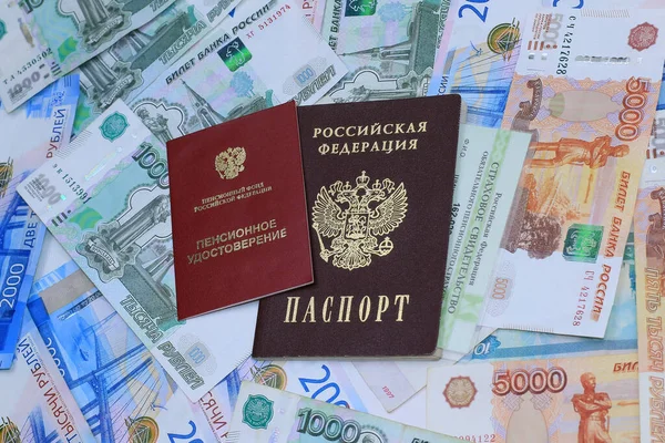 Belgeler: Emeklilik sertifikası, zorunlu emeklilik sigortası belgesi ve Rus parasının arka planında Rus pasaportu