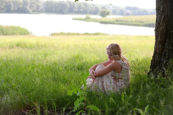 Een meisje zit in een boom — Stockfoto