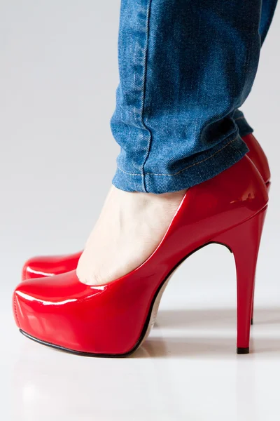 Red high heels shoes and blue jeans — Stock Photo, Image