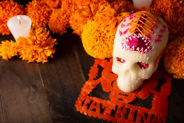 Sugar skull with Candles, Cempasuchil flowers or Marigold and Papel Picado. Decoration traditionally used in altars for the celebration of the day of the dead in Mexico