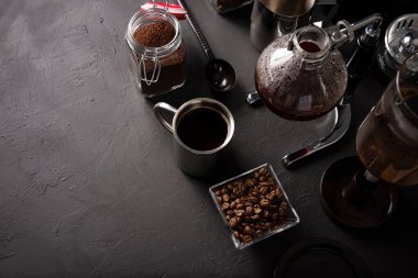 Elektrik süpürgesi, sifon ya da sifon kahve makinesi olarak da bilinir. Metalik fincan ve kavrulmuş kahve çekirdekleri kırsal siyah taş masada. Metnin için boşluk kopyala