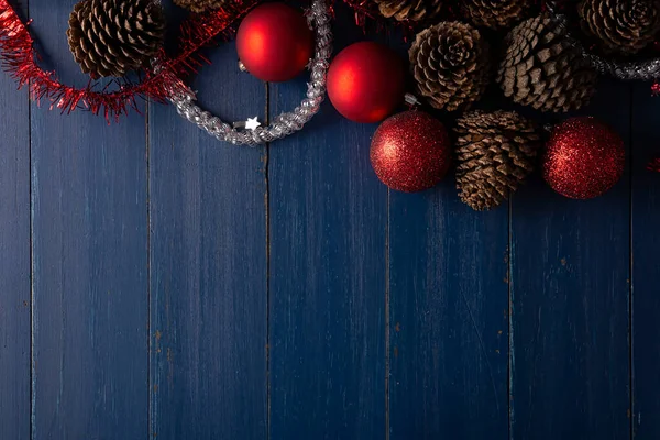 ヴィンテージブルーの木の背景にクリスマスの装飾のためのパインコーンと赤いクリスマスボールのトップビュー テキストのスペースをコピー — ストック写真