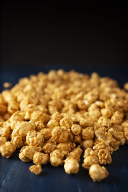 Heap of Caramel Corn on blue rustic table and black background with copy space for your text