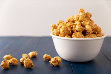 Caramel Popcorn in white bowl on rustic blue wooden table. Close up. Copy space for your text