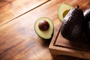 Yarı Meksika avokadosu (persea americana) kırsal ahşap masada. Guacamole hazırlamak için ana malzeme. Resmi kapat