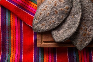 Meksika renkleri kumaşında Tlacoyos. Meksika öncesi İspanyol yemeği. Mavi mısır unlu börek. İçi yeniden kızartılmış fasulye dolu. Meksika 'da popüler sokak yemekleri.