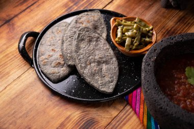 Comal 'ın üzerinde Tlacoyos. Meksika öncesi İspanyol yemeği. Mavi mısır unlu börek. İçi yeniden kızartılmış fasulye dolu. Meksika 'da popüler sokak yemekleri.
