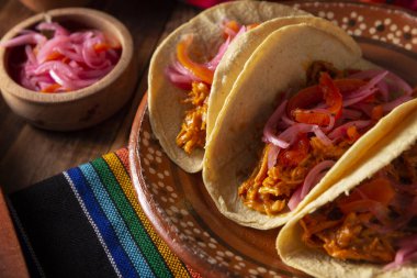 Tacos de Cochinita Pibil. Yucatan 'dan tipik Meksika güveci, fındıklı terbiye edilmiş domuz eti ve yanında fasulye ve kırmızı soğanlı habanero biberi.