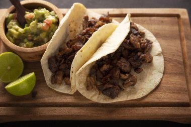 Tacos de Bistec. Homemade grilled meat in a corn tortilla. Street food from Mexico, traditionally accompanied with cilantro, onion and spicy sauce or guacamole