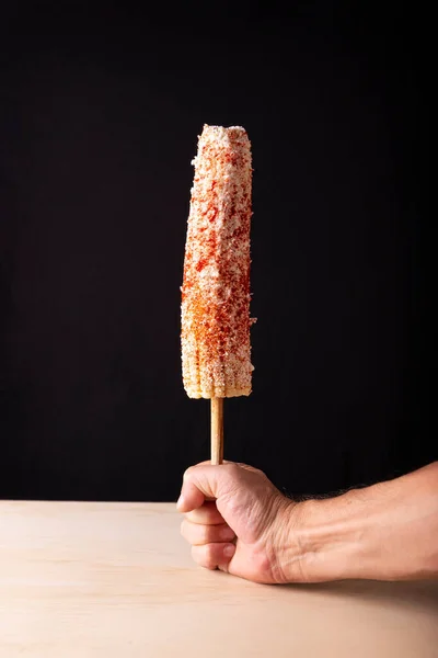 Mexican Street style corn cob are a popular street snack in Mexico, it is tender corn cooked with spices, skewered on a wooden stick covered with mayonnaise or sour cream, fresh cheese and piquin chili powder.
