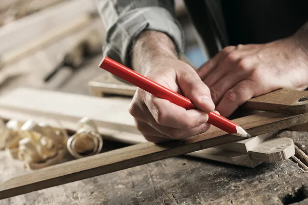 Carpintero marcando un tablón de madera — Foto de Stock