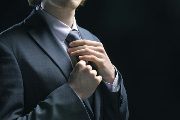 Business man adjusting tie