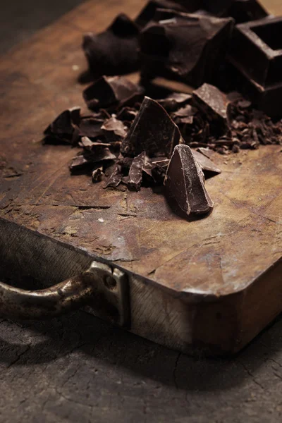 Pieces of dark chocolate on a wooden background — Stock Photo, Image