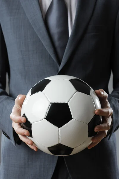 Eleganter Geschäftsmann in der Hand eines Fußballs — Stockfoto