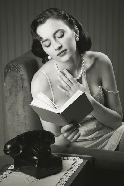 Sensuell kvinna bär underkläder läser en bok på fåtölj — Stockfoto