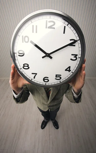 Man holds a clock hiding her face — Stock Photo, Image