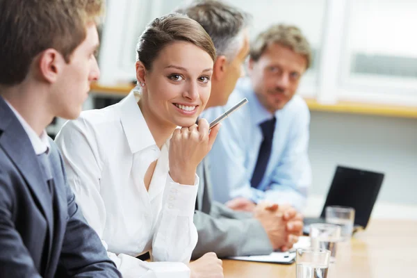 Smiling woman sitting at a business meeting with colleagues — Stock Photo, Image