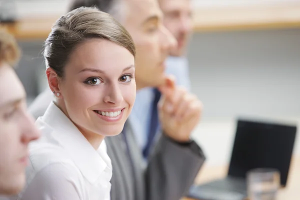 Smiling woman sitting at a business meeting with colleagues — Stock Photo, Image