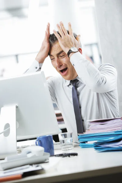 Gefrustreerd zakenman zitten aan de balie in kantoor — Stockfoto