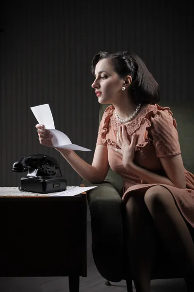 Jonge vrouw lezen van een brief zittend op leunstoel — Stockfoto