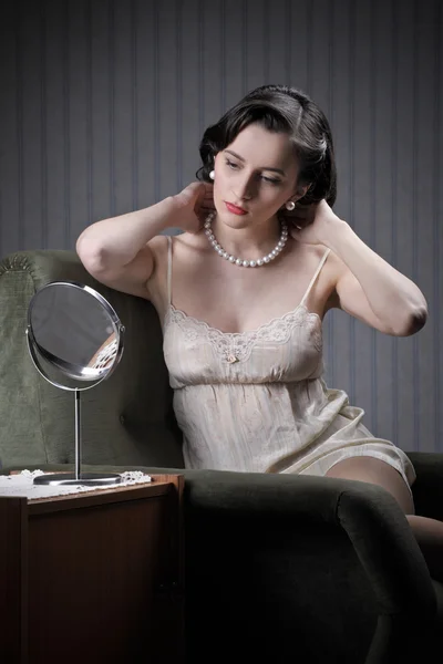 Mujer joven examinando maquillaje en el espejo — Foto de Stock