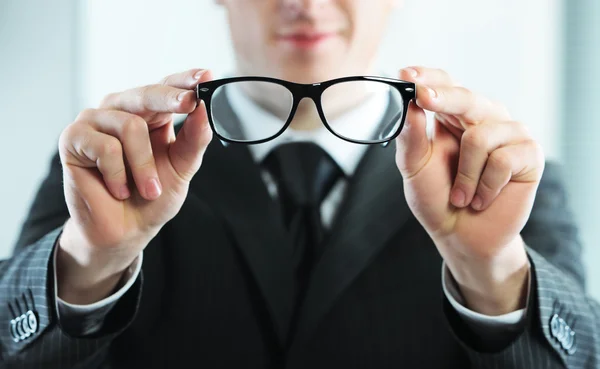 Primer plano de un hombre sostiene gafas — Foto de Stock