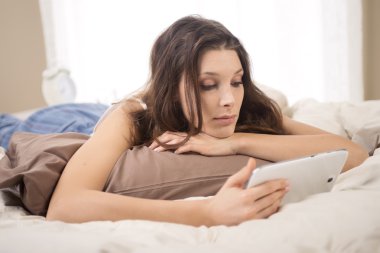 yatakta dijital tablet kullanan kadın