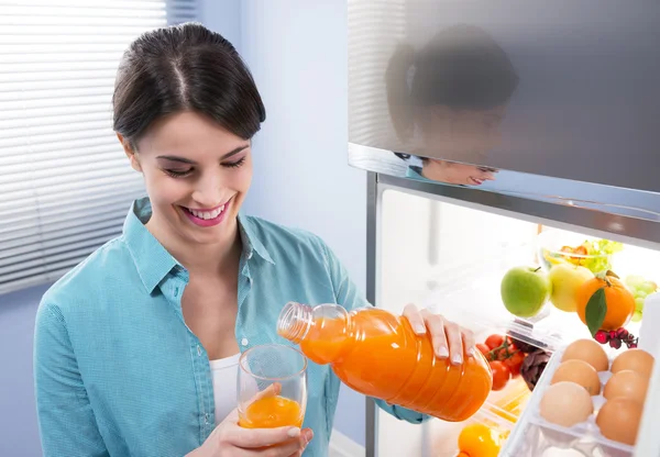 Jovem alegre derramando suco de frutas frescas — Fotografia de Stock