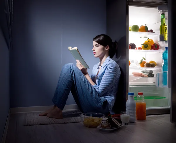 Slapeloze vrouw leest in de keuken — Stockfoto