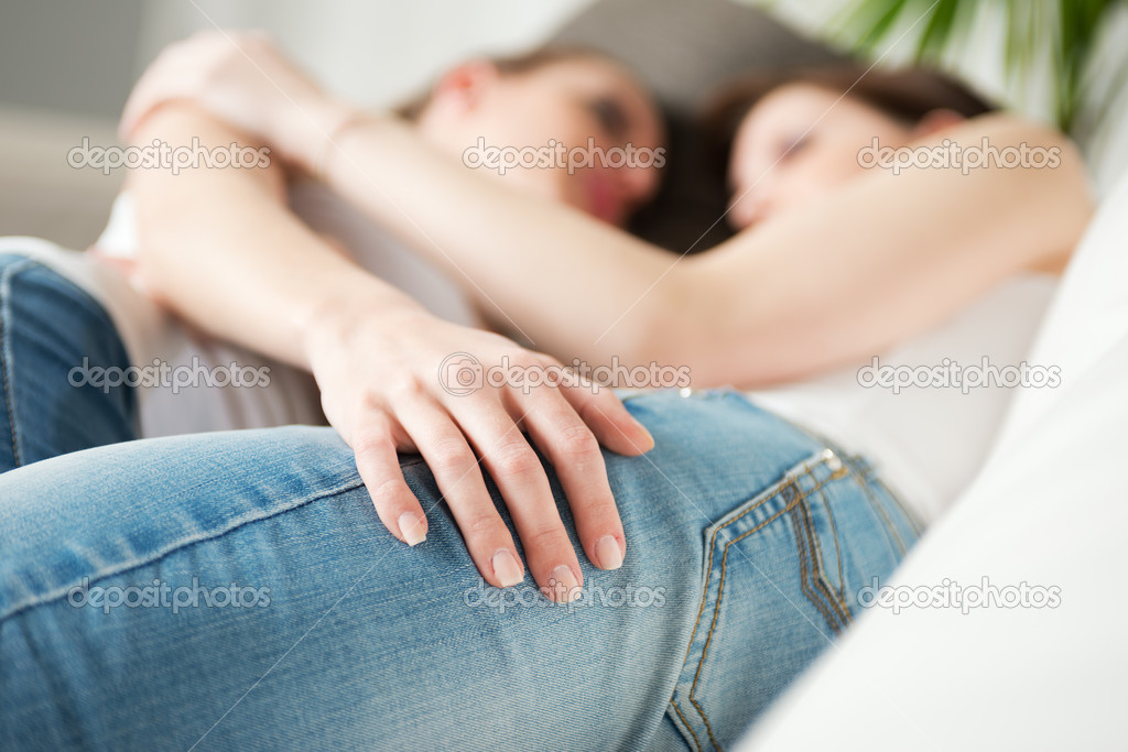 Lesbian couple hugging on sofa