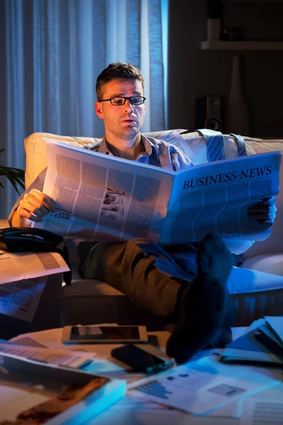 Businessman reading newspaper late at night — Stock Photo, Image